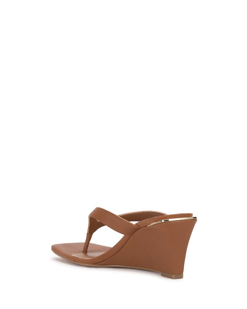 The Vince Camuto Cianna Wedge Sandal features a brown thong strap, low wedge heel, and minimalist design with a subtle metallic accent at the back, shown from a rear side angle against a white background.