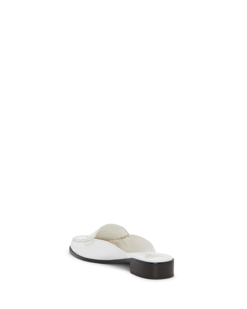 The Vince Camuto Cobby Mule is a white slip-on sandal featuring a classic silhouette and a low dark sole, shown from the back at an angle against a plain white background.