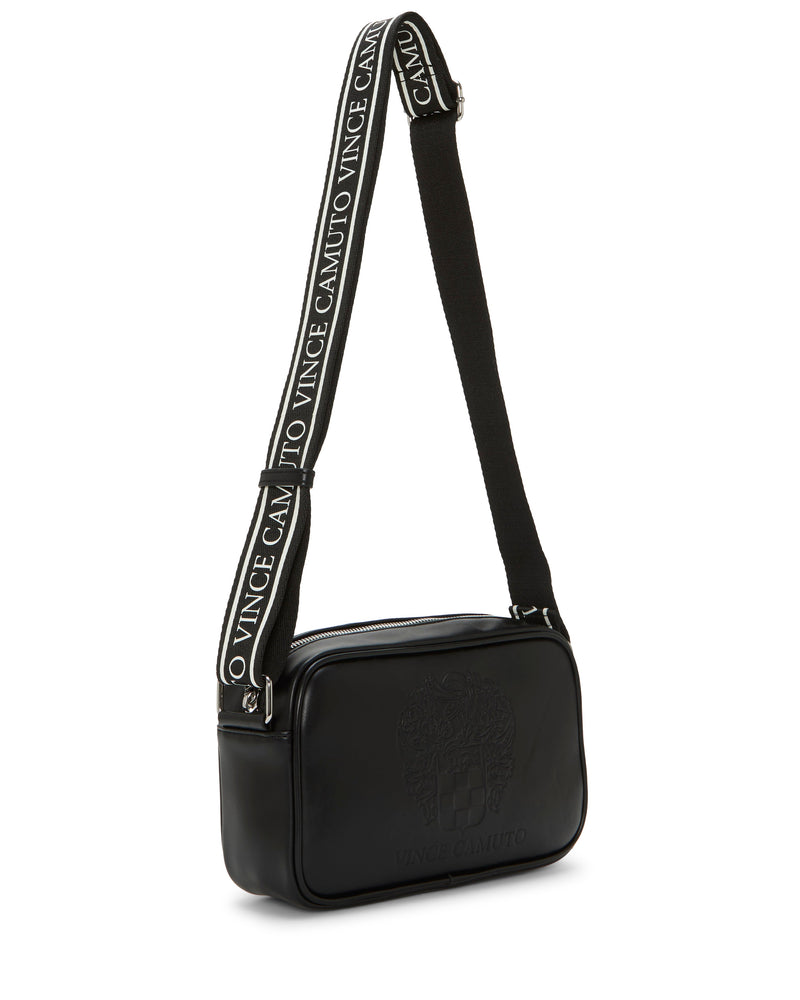 The Dalle Crossbody Bag by Vince Camuto is a black, rectangular camera bag featuring an embossed crest on the front. It comes with a wide logo webbing strap showcasing ‘Vince Camuto’ in white lettering and is finished with sleek silver hardware and a zippered top closure.
