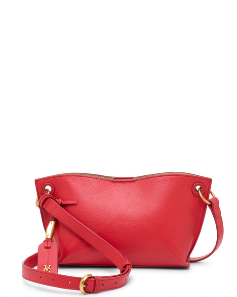 The Ellah Crossbody Bag by Vince Camuto features vibrant red textured leather, gold hardware, an adjustable shoulder strap, a decorative tag, and a simple yet elegant design.