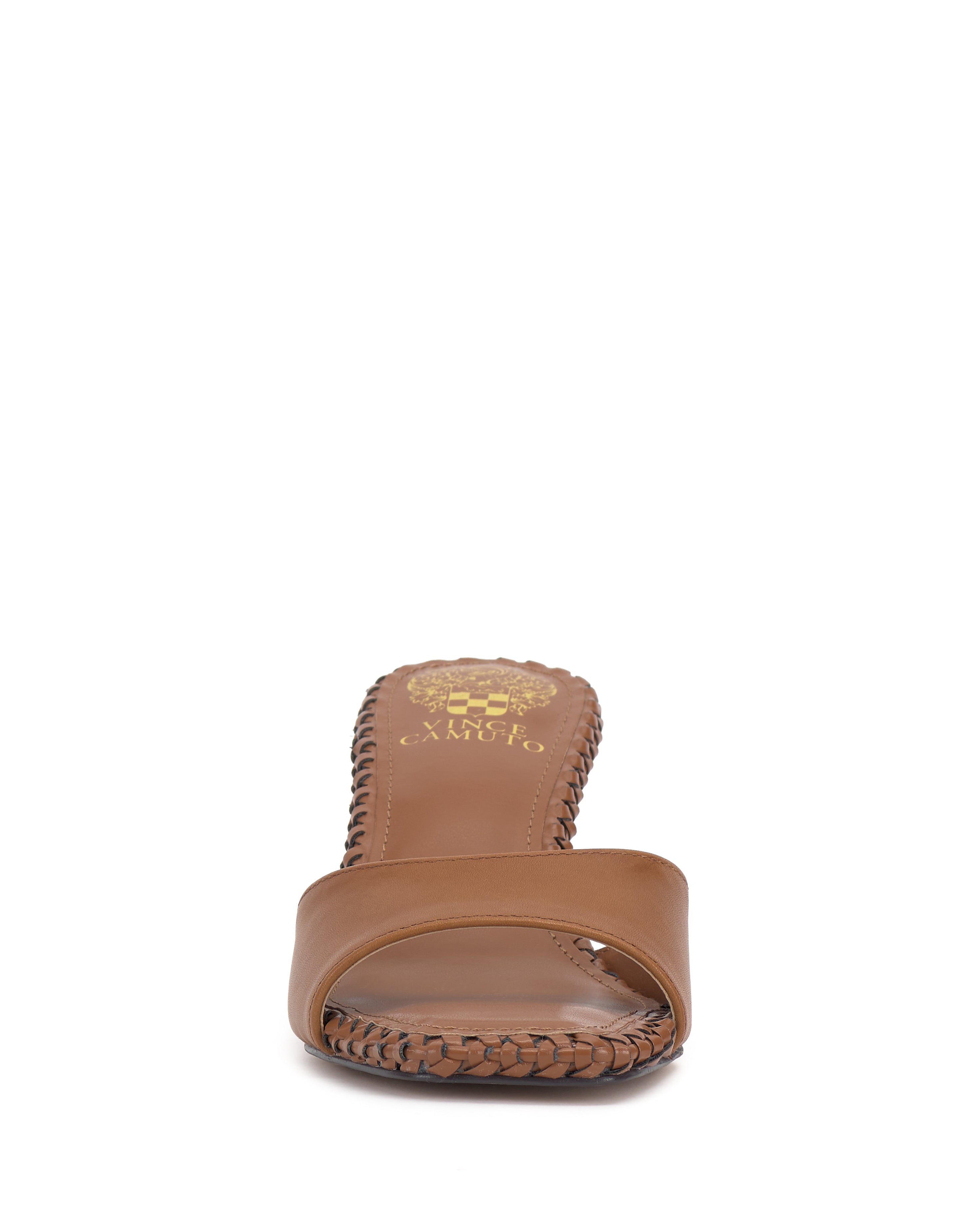 The Emmla Mule by Vince Camuto is a brown open-toe sandal with braided edge detailing, shown from the front. It features a tan insole with a gold logo at the heel, merging modern elegance and classic style.