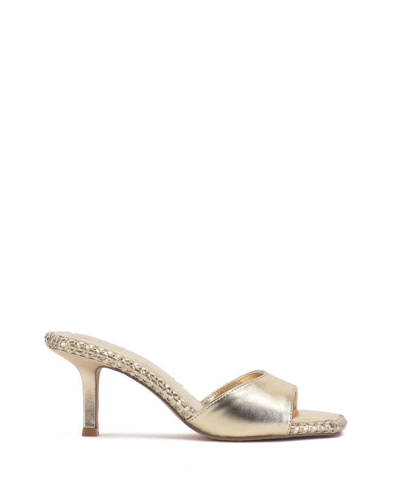 The Vince Camuto Emmla Mule is a gold open-toe sandal featuring a mid-height stiletto heel and metallic sole trim, displayed on a white background for a modern, elegant vibe.