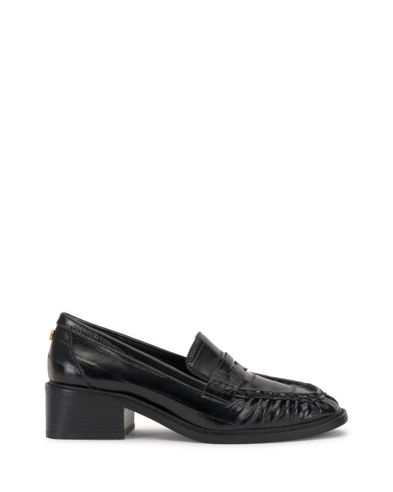 The Vince Camuto Eshnie Block Heel Loafer is a black loafer with a low block heel, penny strap detail, and stitched toe accents, shown in side profile on a white background.