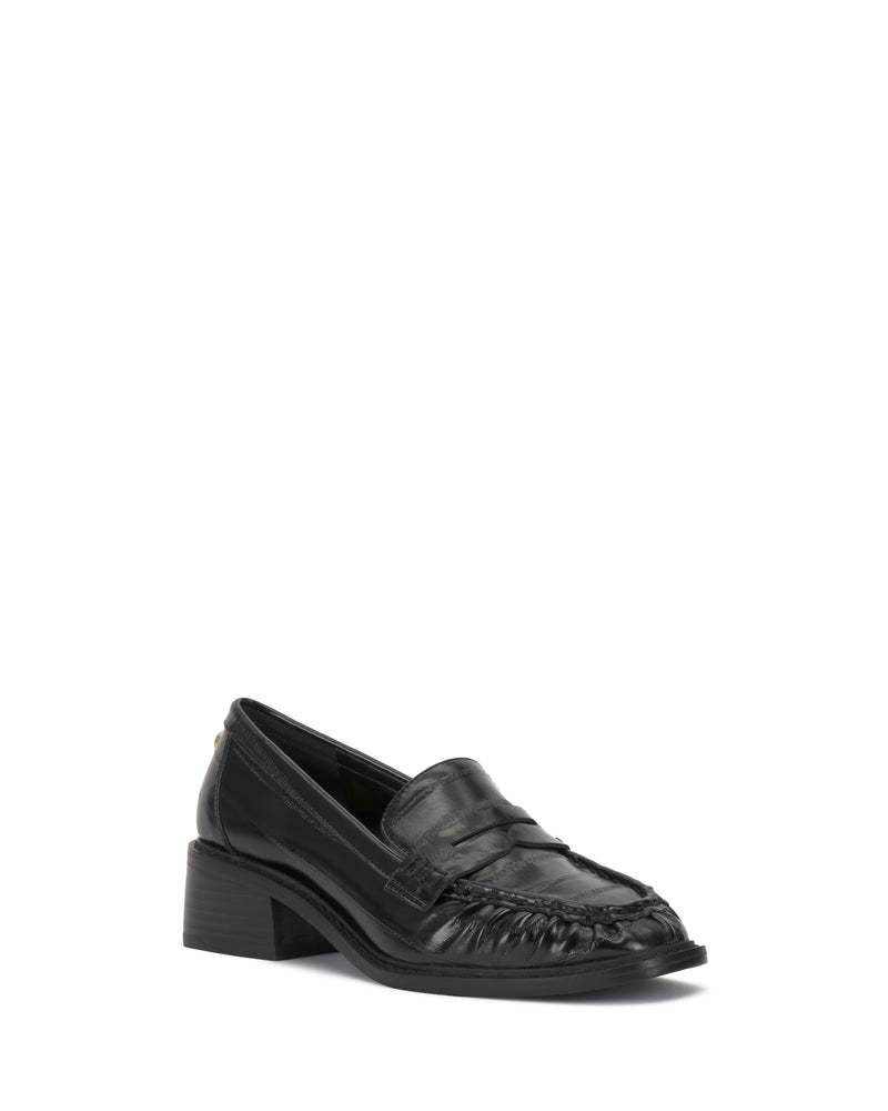 The Vince Camuto Eshnie Block Heel Loafer in black features a low block heel and subtle reptile embossing on the toe, shown against a white background.