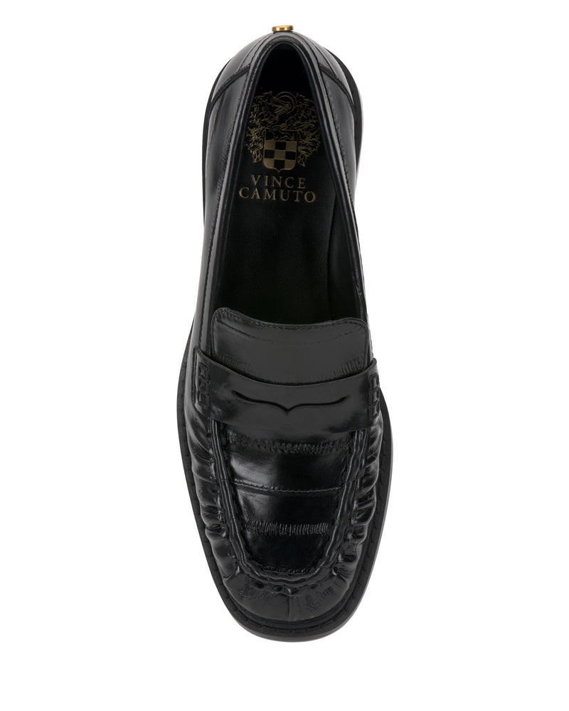 The Eshnie Block Heel Loafer by Vince Camuto features a stitched moc toe, smooth black leather upper, subtle block heel, and a gold Vince Camuto logo on the insole.