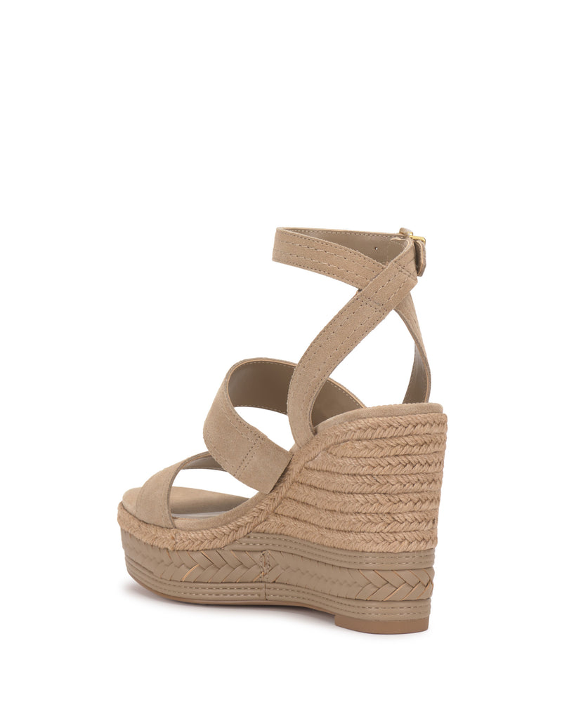 The Vince Camuto Esmia Espadrille Wedge Sandal features tan suede straps, an open toe, a back buckle ankle strap, and a braided espadrille platform with a textured woven wedge heel.