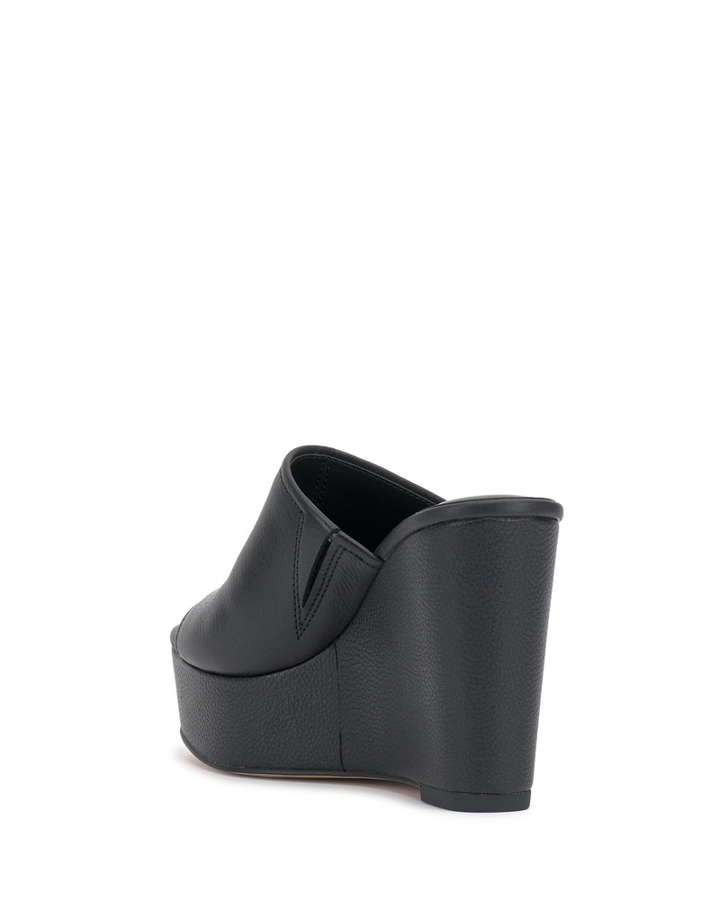 The Etta Wedge Sandal by Vince Camuto is a black, single-banded open-back mule with a peep toe and textured leather wedge heel, shown from the rear against a white background.