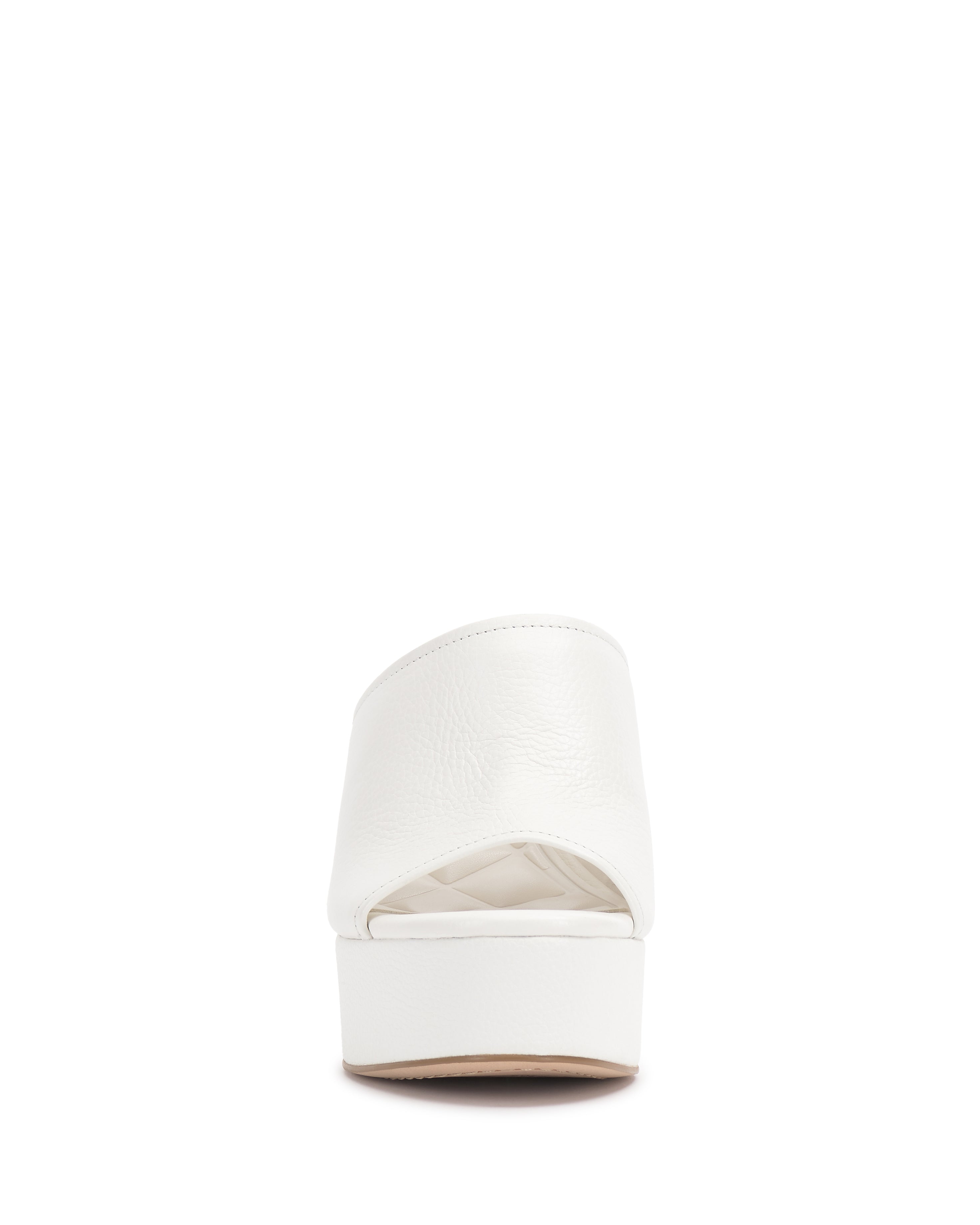 The Vince Camuto Etta Wedge Sandal is shown from the back, displaying its white Y2K-inspired closed heel, textured upper, and flat sole. The sandal is set against a plain white background.