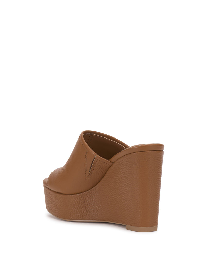 The Vince Camuto Etta Wedge Sandal features brown leather, a single banded peep toe design, and a textured platform sole, shown from the back right against a white background.