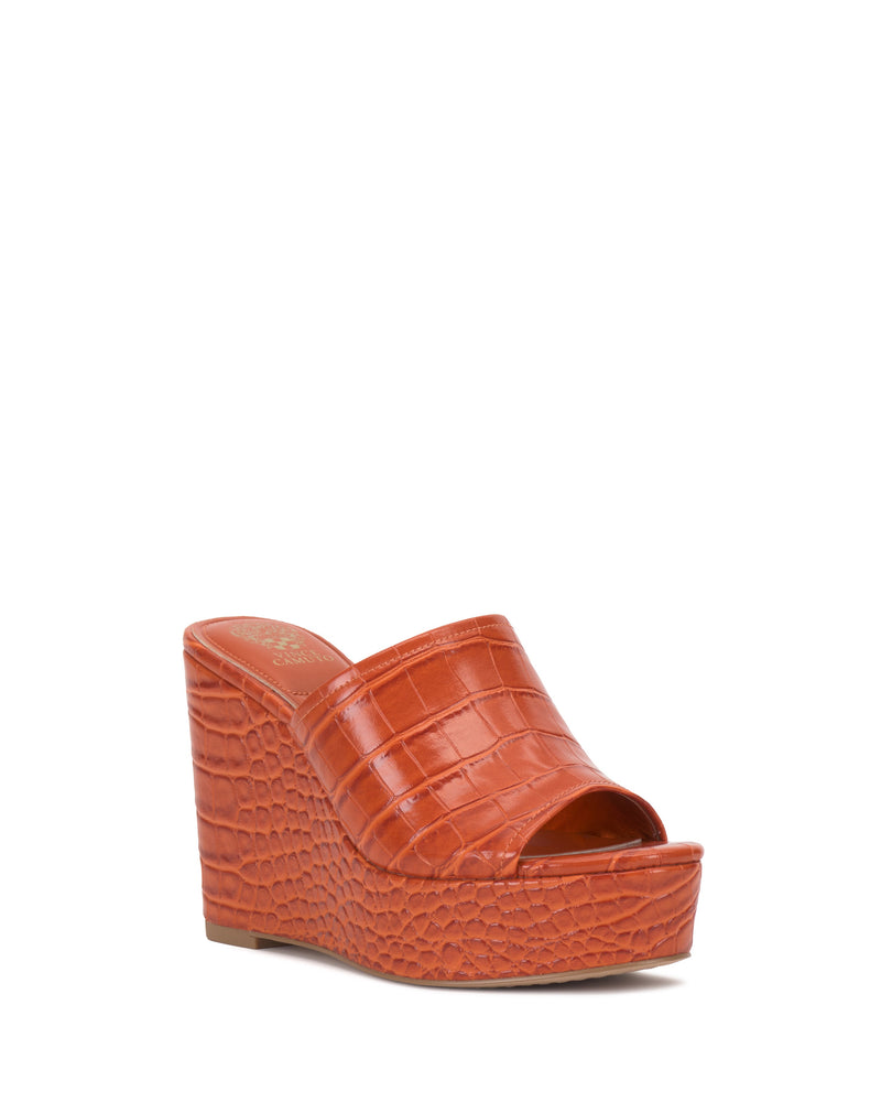 The Vince Camuto Etta Wedge Sandal features a Y2K-inspired orange faux crocodile texture, single band design, open toe, and slip-on style, shown on a white background.