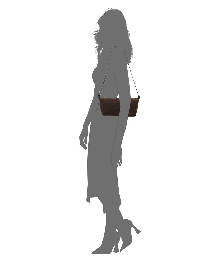Silhouette of a person in a dress and heels carrying the Vince Camuto Faey Shoulder Bag, a rectangular handbag with a thin strap, set against a white background.