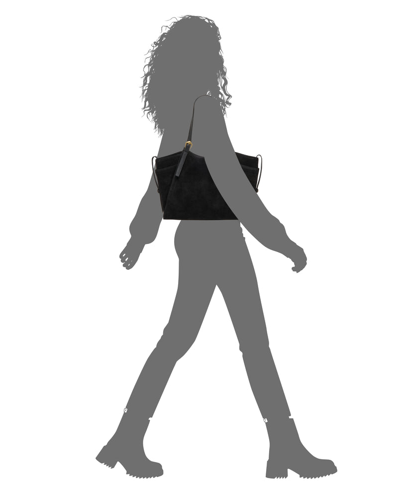 A silhouette of a person walking, wearing boots and carrying the Vince Camuto Faey Tote Bag on their shoulder against a white background.