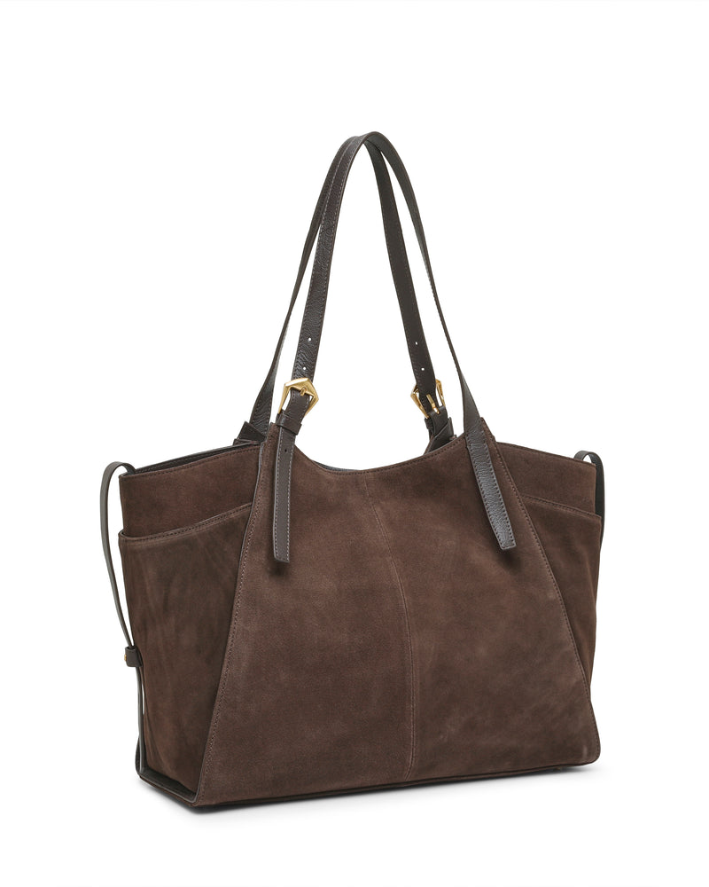 The Vince Camuto Faey Tote Bag, crafted from brown suede with two dark leather handles, gold-tone hardware, and side pockets, stands upright against a white background.