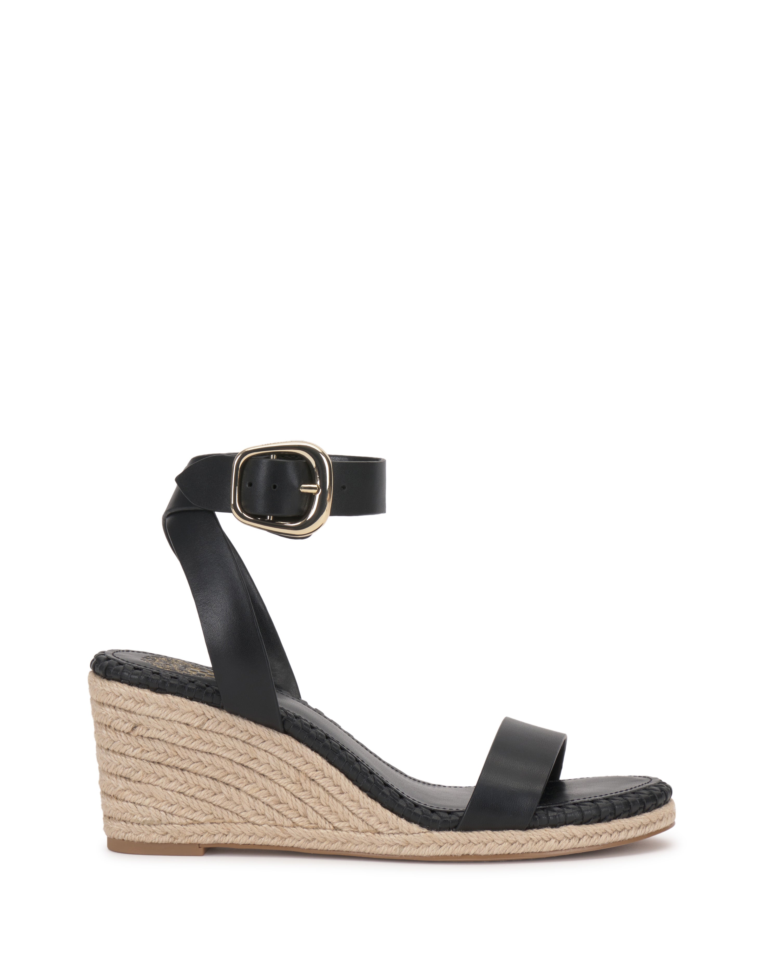 The Vince Camuto Fainel Espadrille Wedge Sandal is a black summer sandal with an espadrille wedge heel, woven jute platform, ankle strap with gold buckle, simple toe strap, and a natural straw-textured wedge.