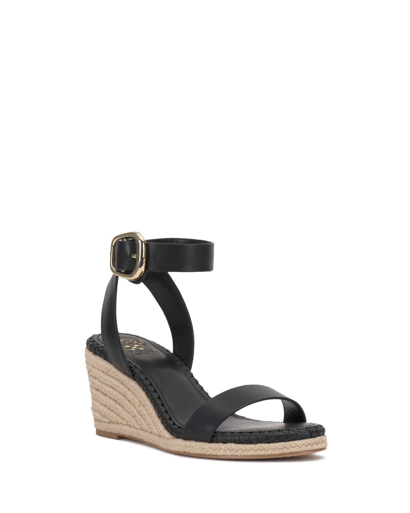 The Vince Camuto Fainel Espadrille Wedge Sandal features a black ankle strap, gold buckle, and woven sole, shown on a white background for a chic summer look.