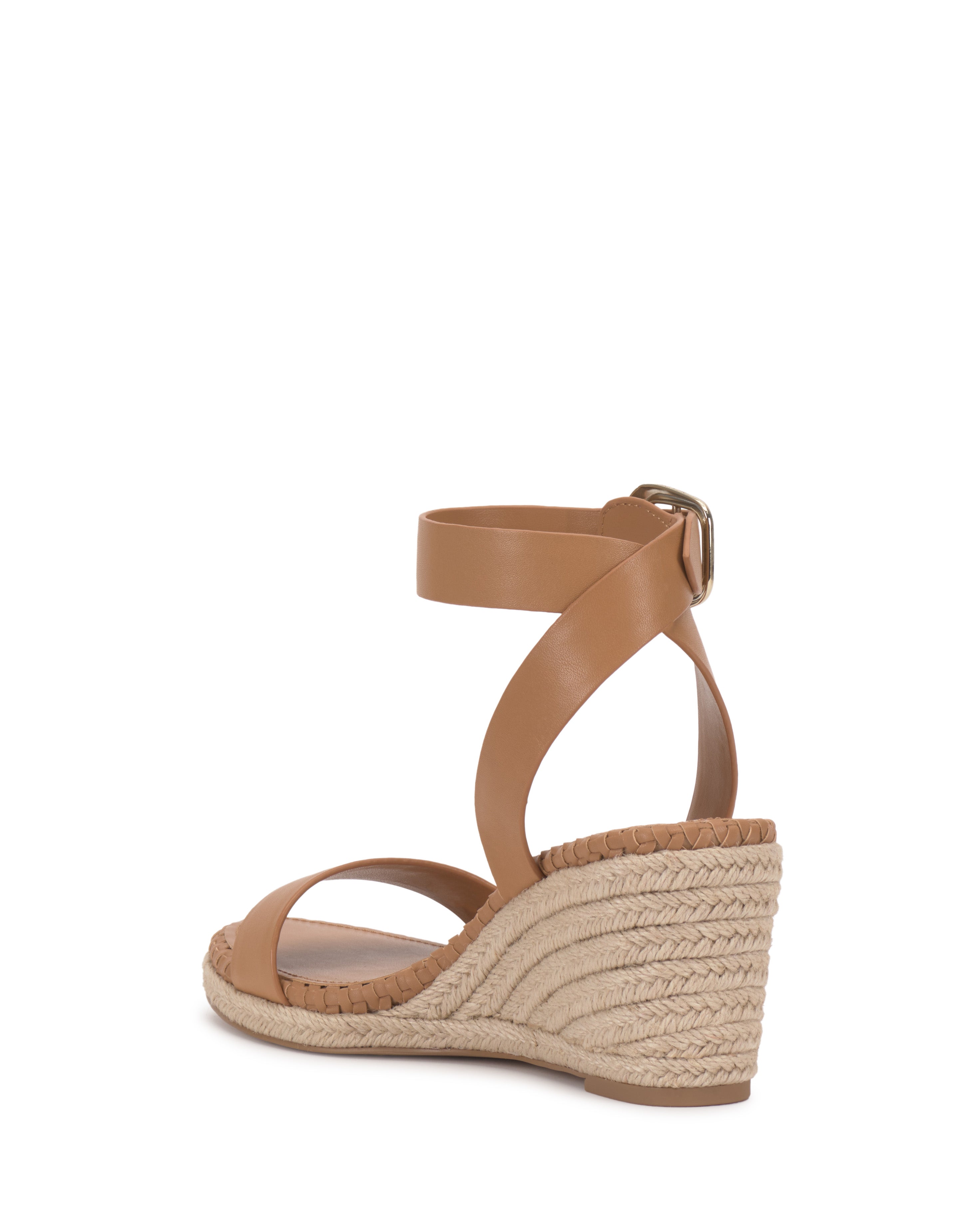 The Vince Camuto Fainel Espadrille Wedge Sandal features a tan strappy upper, bold buckle closure, and woven espadrille heel, all displayed with a minimalist look against a plain white background.
