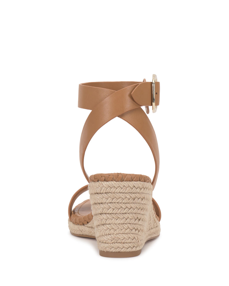 Rear view of the Vince Camuto Fainel Espadrille Wedge Sandal in tan, showcasing a strappy upper with a bold buckle, woven espadrille wedge heel, and textured sole, set against a white background.