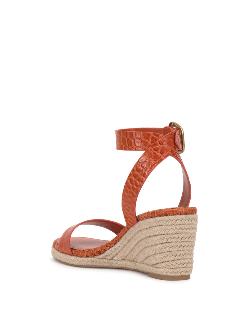 The Fainel Espadrille Wedge Sandal by Vince Camuto features orange textured uppers, an ankle strap with a gold buckle, and a woven platform heel for a summery look, displayed against a white background.