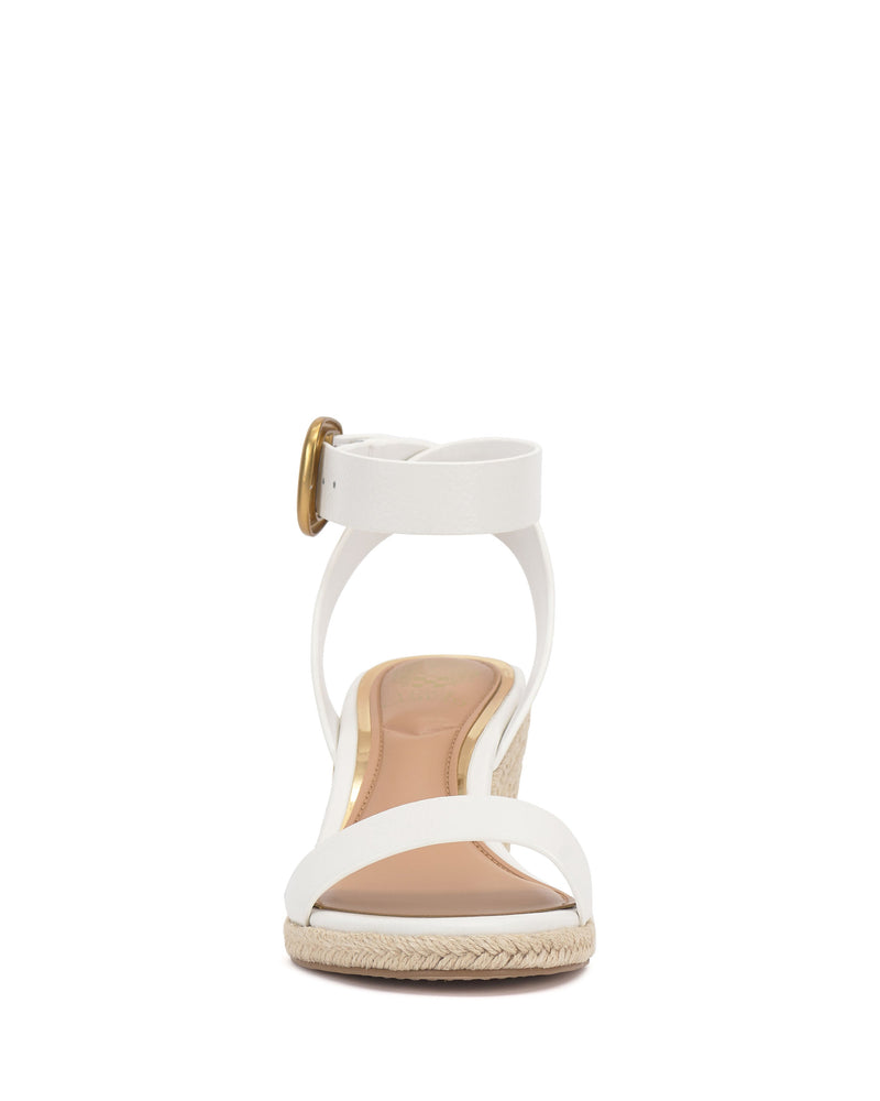 Front view of the Vince Camuto Felia Espadrille Wedge Sandal featuring a white leather upper, ankle strap with gold buckle, low espadrille wedge heel, and woven sole detail.