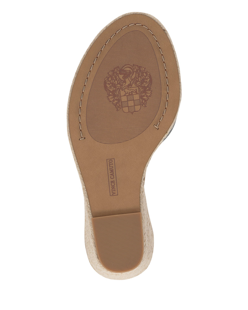 The image displays the sole of the Vince Camuto Felyn Espadrille Wedge Sandal with a crest design, brand name imprint, slightly raised beige espadrille heel, and visible stitching around the edge.