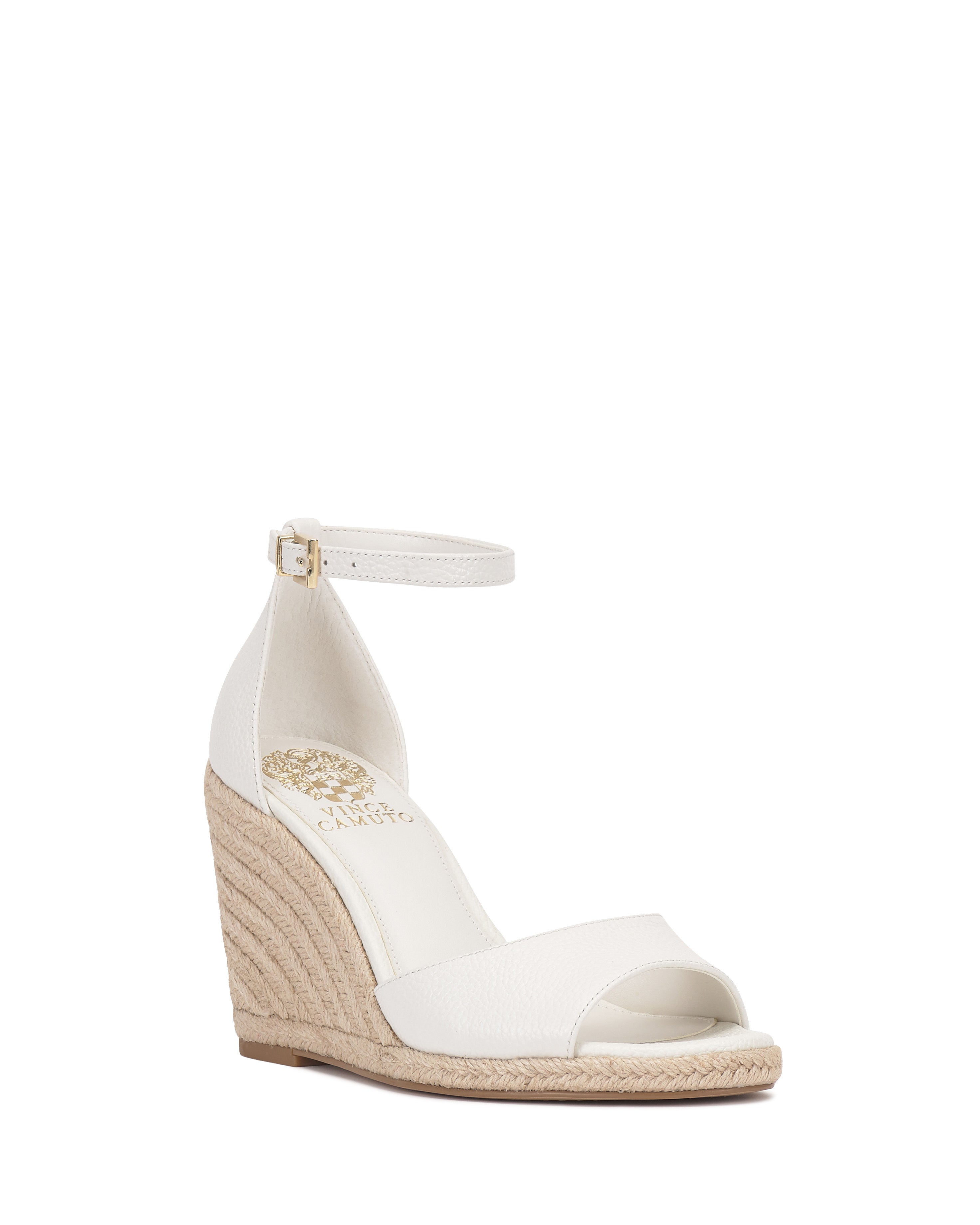 The Felyn Espadrille Wedge Sandal by Vince Camuto features an open toe, ankle strap with buckle, white upper, woven espadrille heel, and gold-branded insole for a simple, elegant look.