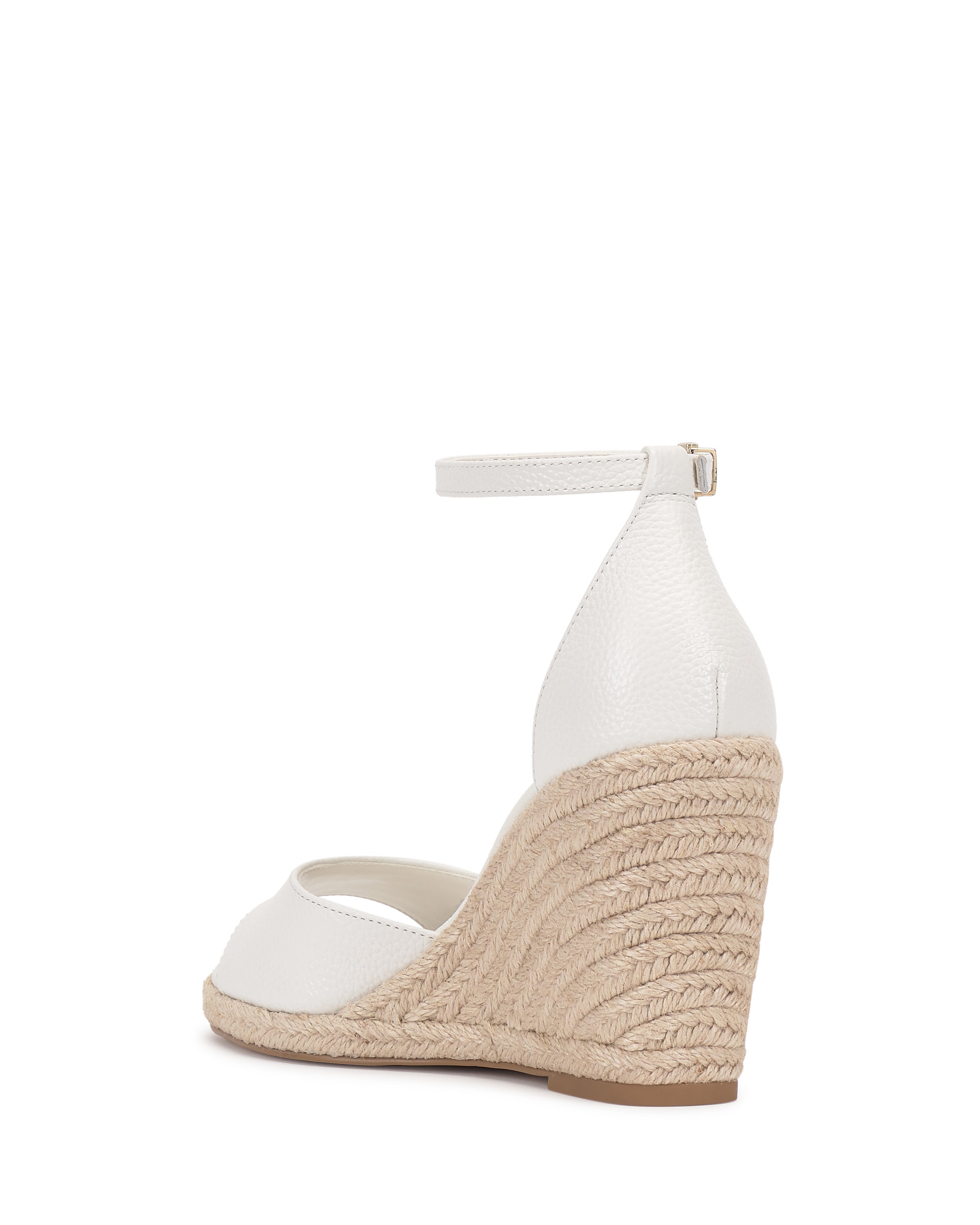 The Vince Camuto Felyn Espadrille Wedge Sandal features a white upper, ankle strap with buckle, closed heel, and natural-colored braided jute wedge for classic espadrille style.