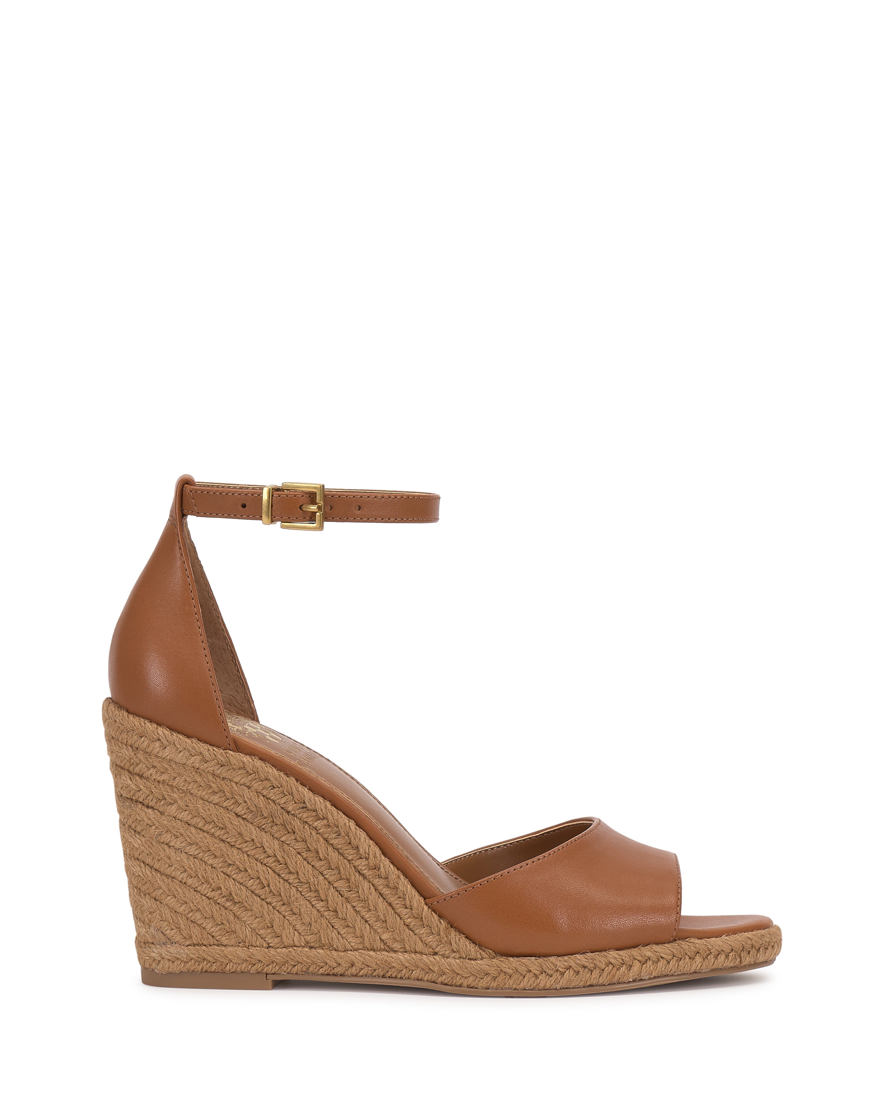The Vince Camuto Felyn Espadrille Wedge Sandal features brown leather, an ankle strap with buckle, a woven espadrille heel, and an open toe. Displayed against a plain white background.