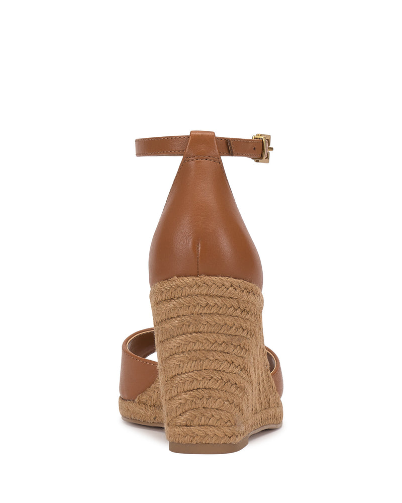 The Vince Camuto Felyn Espadrille Wedge Sandal is shown from the back, featuring brown leather, an ankle strap, and a braided espadrille heel against a white background.