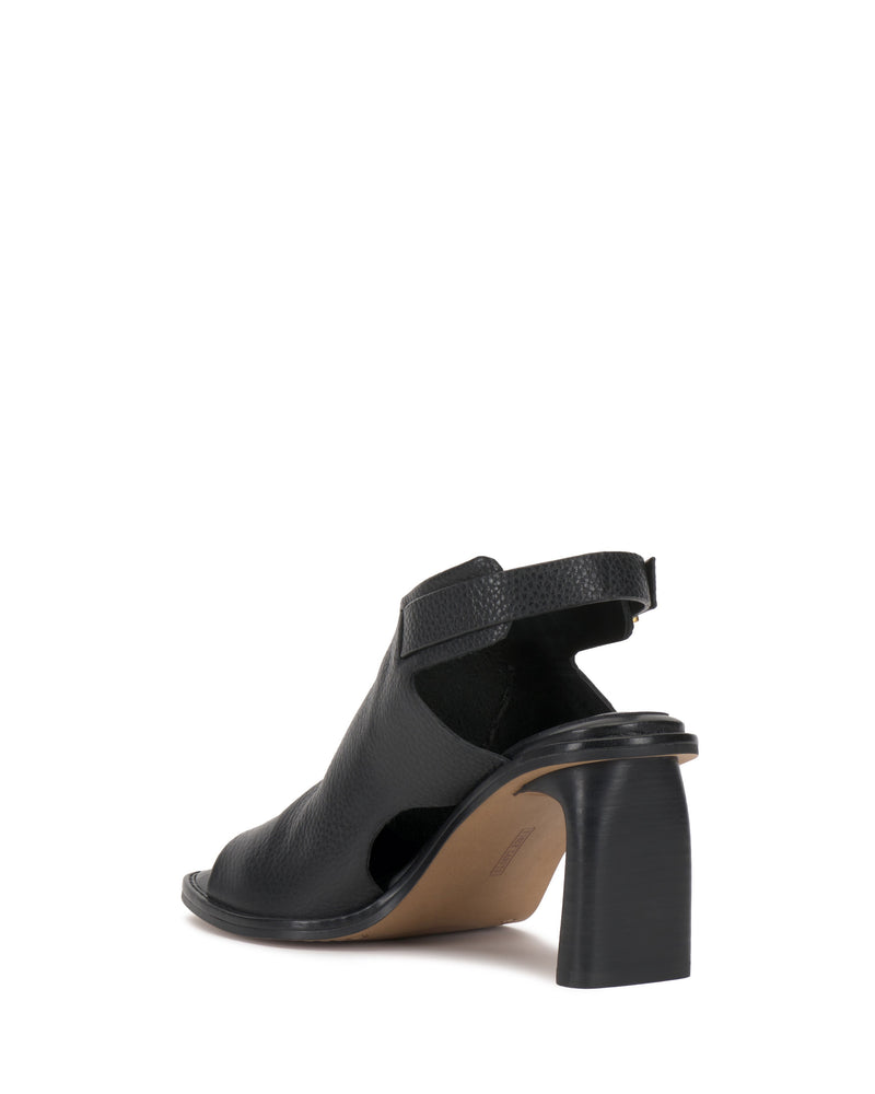 The Vince Camuto Fezisha Sandal is a black open-toe suede shoe with a textured finish, cutout sides, thick block heel, and ankle strap, displayed from the rear side angle on a white background.