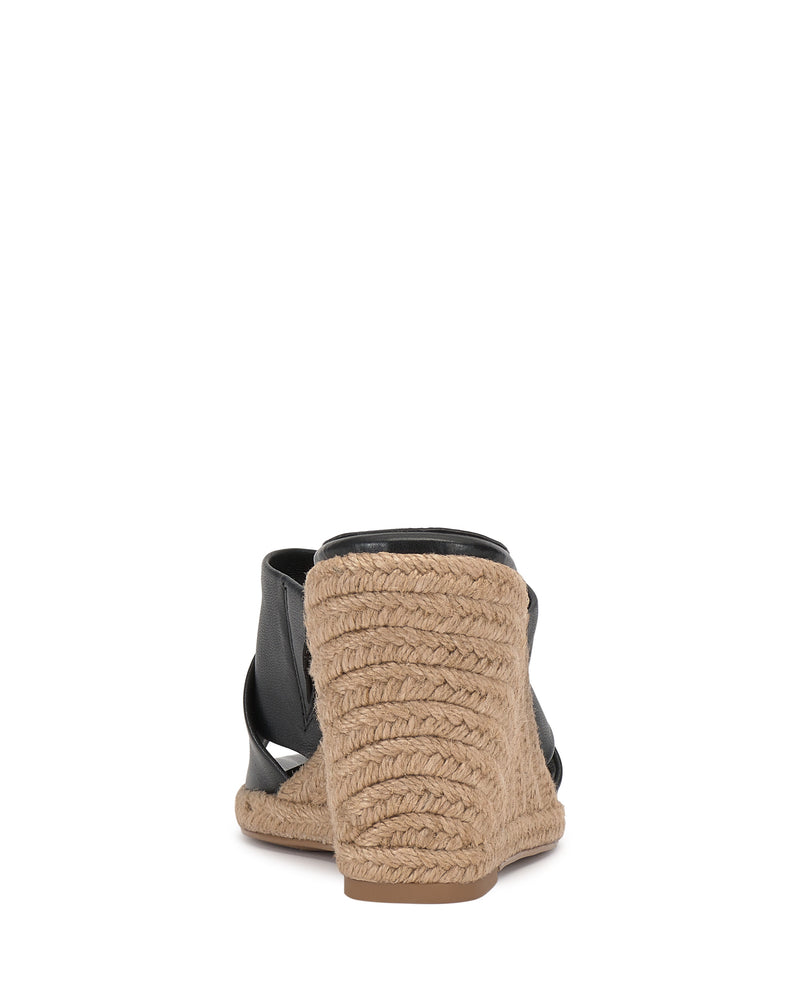 Back view of the Vince Camuto Fisella Espadrille Wedge Sandal, featuring a black upper, braided jute heel, espadrille platform, and tan rubber sole against a white background.