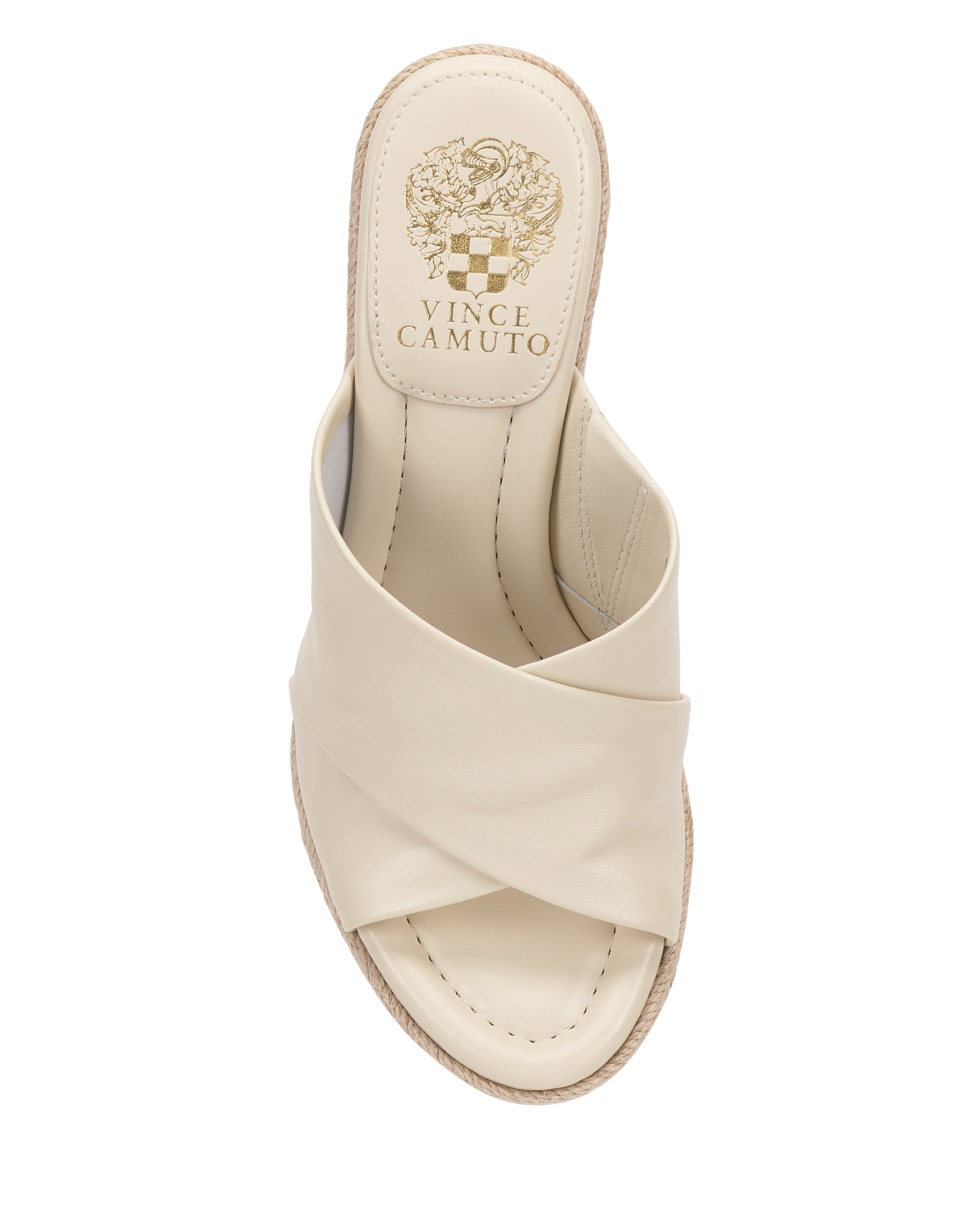 A top view of the cream Fisella Espadrille Wedge Sandal by Vince Camuto featuring a criss-cross leather upper, beige stitching, slip-on style, and the brand’s gold logo on the insole.