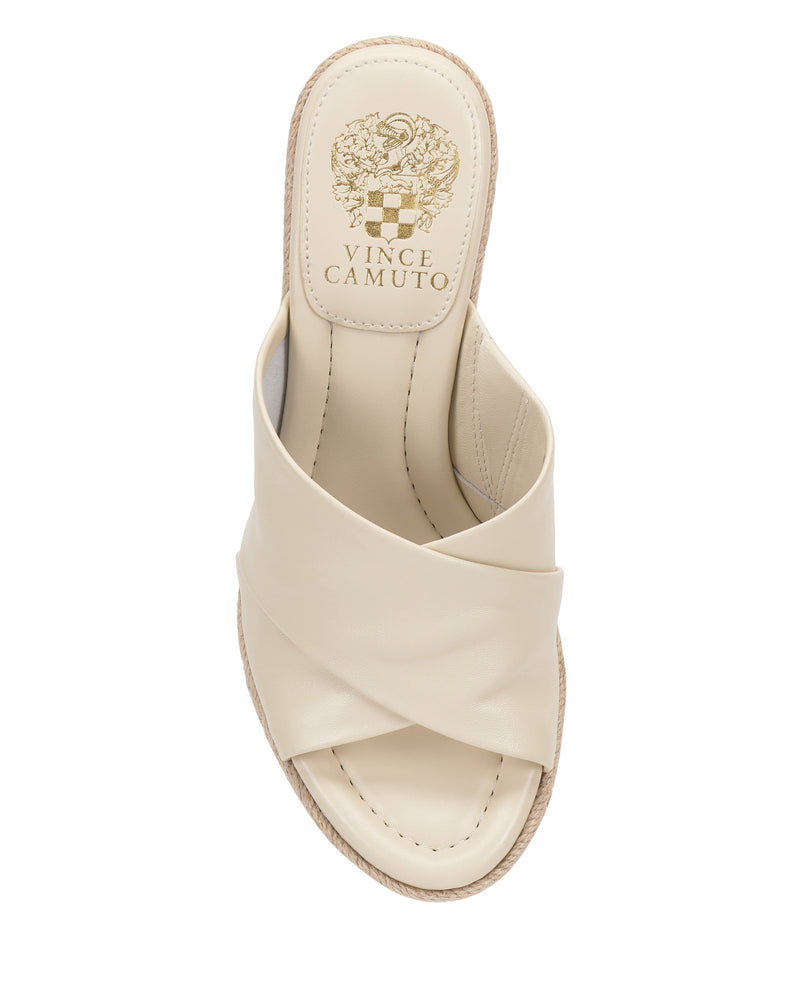 A top view of the cream Fisella Espadrille Wedge Sandal by Vince Camuto featuring a criss-cross leather upper, beige stitching, slip-on style, and the brand’s gold logo on the insole.