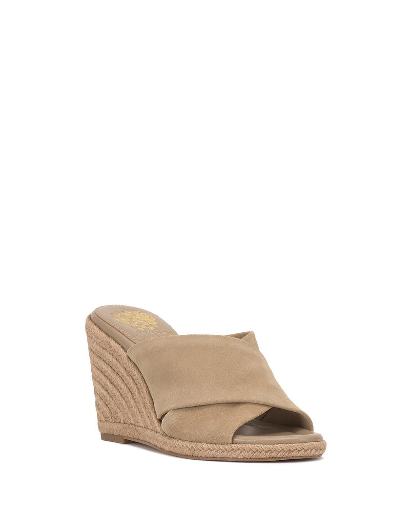 The Vince Camuto Fisella Espadrille Wedge Sandal features a tan suede crisscross strap, a woven platform heel, and an easy slip-on design, displayed against a white background.
