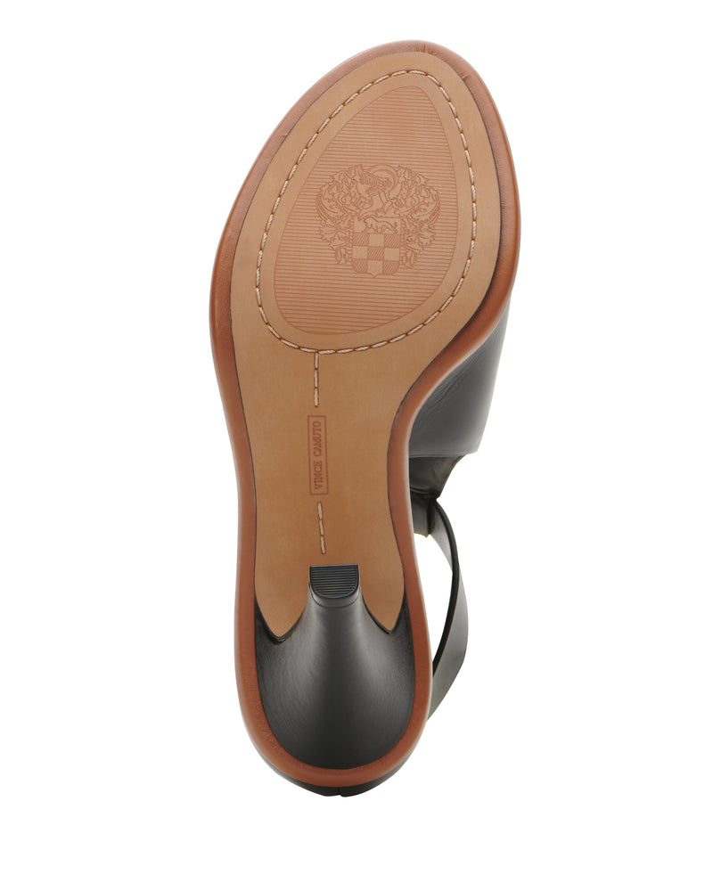 The photo shows the brown sole of the Frasper Shootie by Vince Camuto—a black dress shoe featuring a crest design and stitching detail around the edge, with a comfortably cushioned footbed for all-day support.
