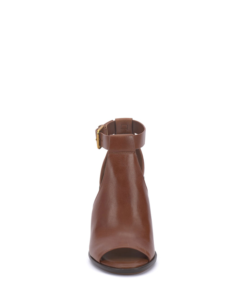 Front view of the Vince Camuto Frasper Shootie, a brown leather peep-toe ankle boot featuring a gold buckle strap around the ankle and a cushioned footbed, displayed on a white background.