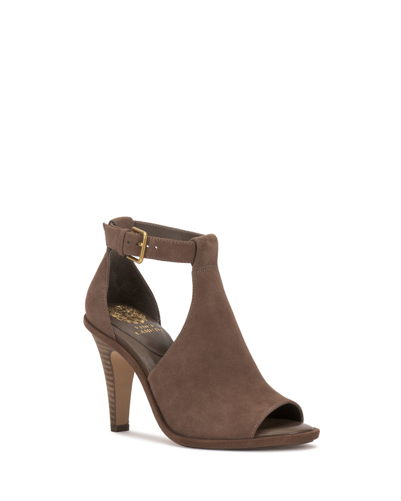 Introducing the Frasper Shootie by Vince Camuto: a brown suede high-heeled peep-toe sandal featuring a stylish T-strap design, ankle strap with a gold buckle, and chic cutout sides. This shoe offers a medium-height, slightly tapered heel and boasts an insole adorned with a decorative gold pattern as well as a cushioned footbed for enhanced comfort.