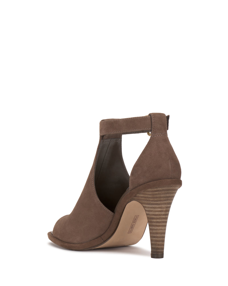 The Frasper Shootie by Vince Camuto is a brown suede high-heeled peep-toe sandal with a classic T-strap silhouette and a stacked heel, shown from the back-right angle against a white background. Designed with a cushioned footbed for enhanced comfort.