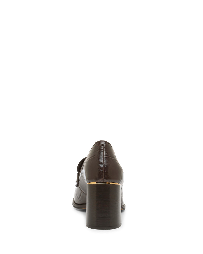 A rear view of the Vince Camuto Geanna Pump shows a brown block heel loafer with a chunky wooden heel and a gold trim detail near the sole, set against a white background—an elegant design.