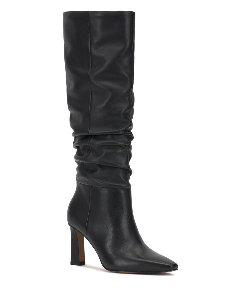 The Vince Camuto Genisa Narrow Calf Slouchy Knee High Boot is shown in black, featuring a pointed toe, slouchy shaft, and high block heel, set against a white background.