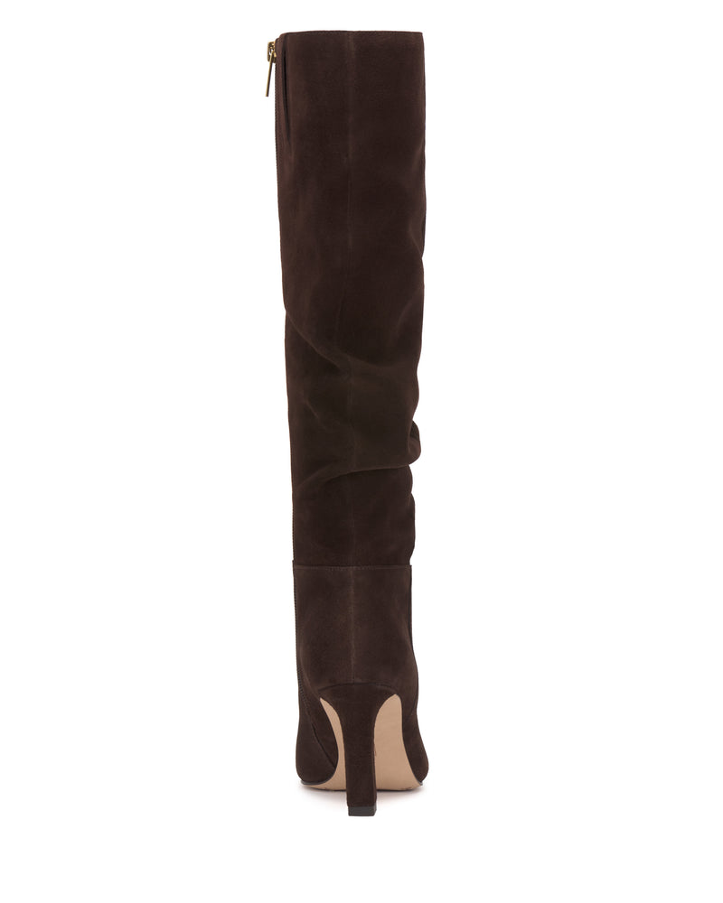 The Genisa Slouchy Knee High Boot by Vince Camuto is a tall brown suede heeled boot, shown from the back, with a side zipper and a slightly pointed toe.
