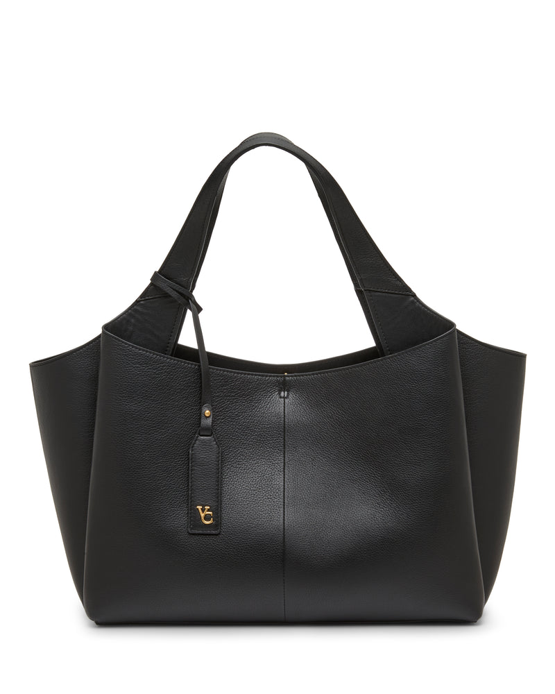 The Gilda Tote Bag by Vince Camuto is a spacious black leather tote featuring wide handles and a gold-tone logo tag, shown against a white background.