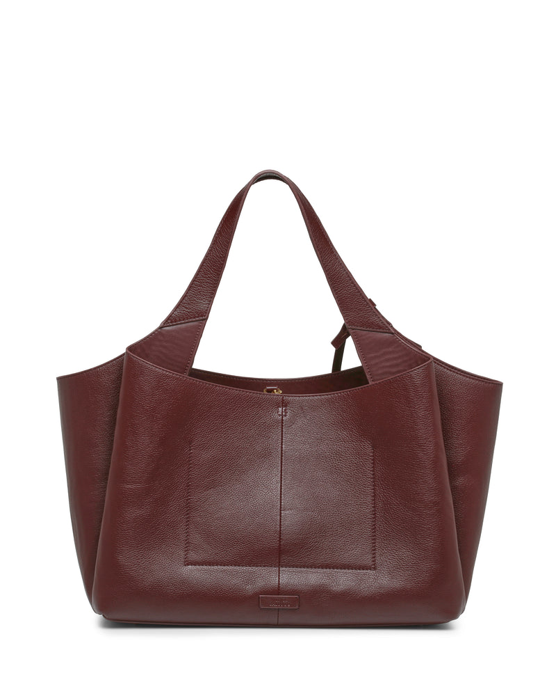 The Gilda Tote Bag by Vince Camuto is a large burgundy leather tote featuring wide handles, a structured shape, and a front pocket. This sophisticated accessory is photographed against a white background.