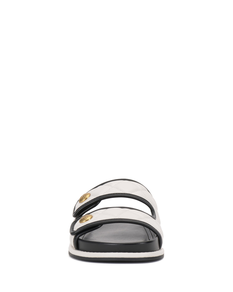 Front view of the Vince Camuto Graysin Slide, a black and white sandal with a quilted upper, two white straps accented by gold-toned buttons, and a flat black sole.
