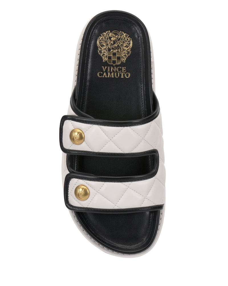 The Vince Camuto Graysin Slide features a single white quilted upper with double Velcro straps, each adorned with gold-toned buttons. The black footbed displays the Vince Camuto logo and crest in gold.