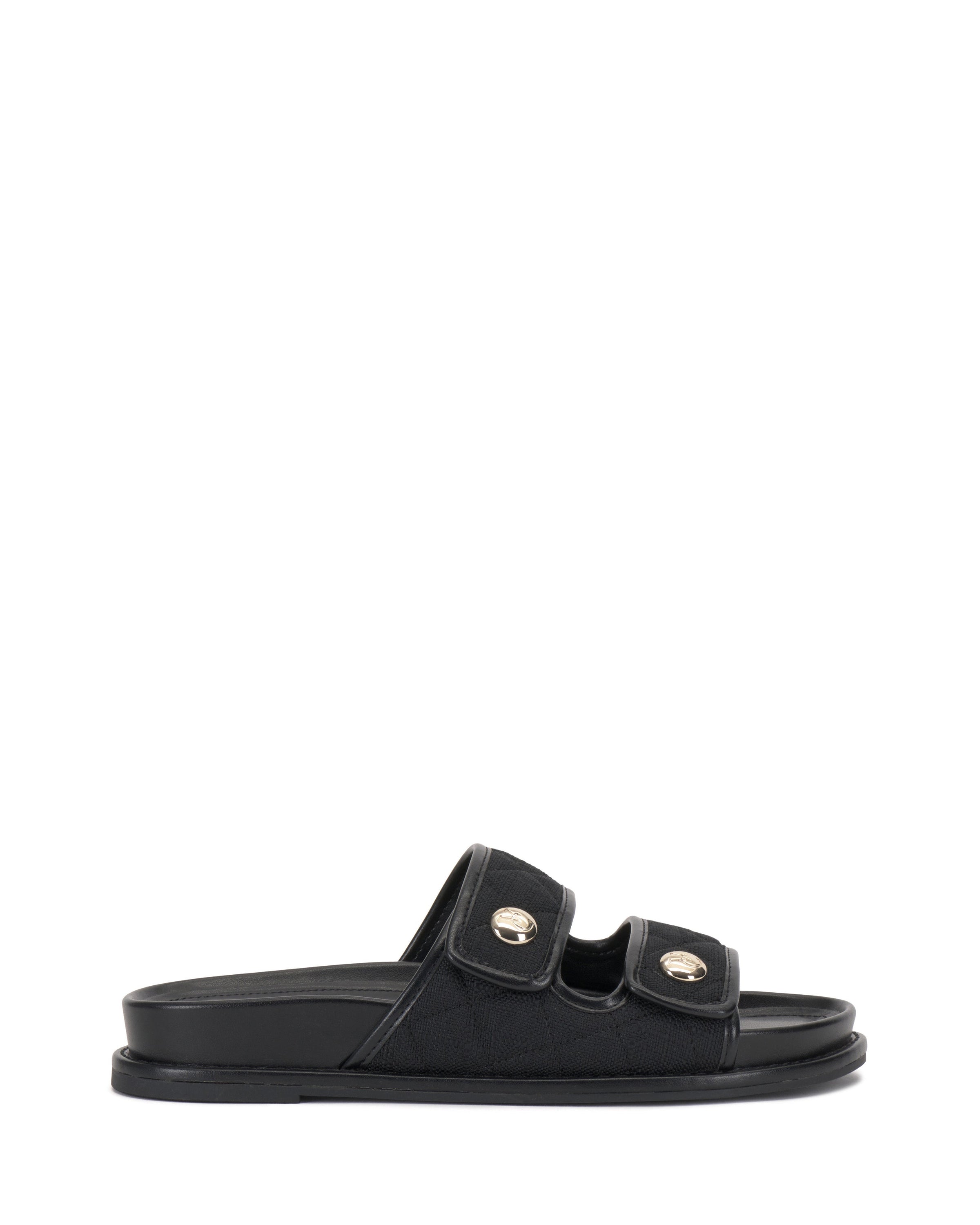 The Graysin Slide by Vince Camuto is a black sandal with a quilted upper, two wide double straps topped with gold-toned buttons, plus an open toe and flat sole.