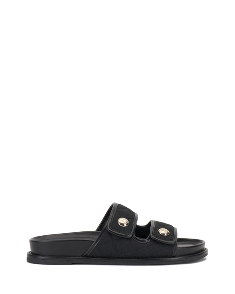 The Graysin Slide by Vince Camuto is a black sandal with a quilted upper, two wide double straps topped with gold-toned buttons, plus an open toe and flat sole.