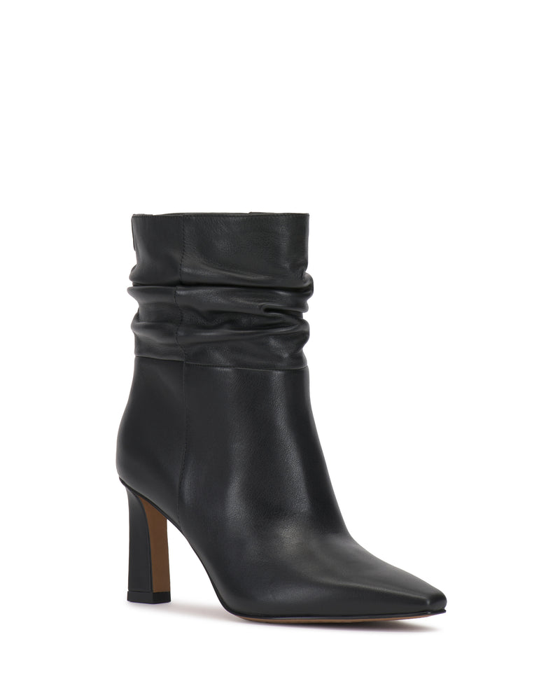 The Vince Camuto Grenna Slouchy Bootie features black leather, a pointed toe, a slouchy upper, and a high block heel. It has a brown sole and is photographed against a plain white background.