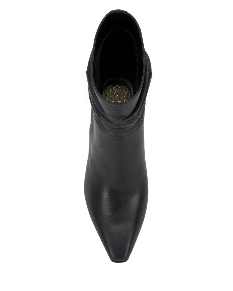 Top view of the Vince Camuto Grenna Slouchy Bootie—a single black leather ankle boot featuring a pointed toe, a slight slouch at the ankle, and decorative gold insole detailing—isolated on a white background.