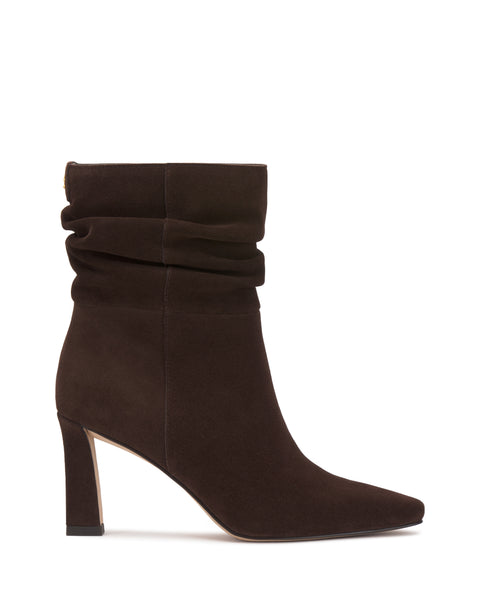 The Vince Camuto Grenna Slouchy Bootie is a brown suede ankle boot featuring a slouchy shaft, pointed toe, and high block heel, displayed on a white background.