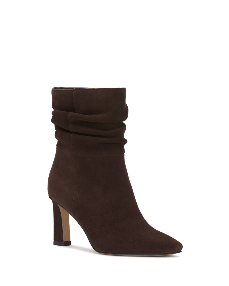 The Grenna Slouchy Bootie by Vince Camuto features brown suede with a slouchy shaft, pointed toe, and high block heel. Its minimalist design, free of visible embellishments, delivers a sleek and stylish look.